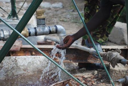 Community member enjoys the first water flowing out of the wind pump
