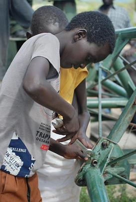 Young boys eager to help tighten bolts of the wind pump